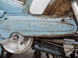 a close up of a blue motorcycle with rust on it