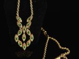 a gold necklace and bracelet set with emerald stones