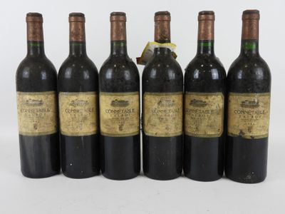six bouteilles de vin sont alignées sur une surface blanche