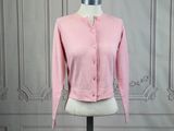 Le cardigan rose est posé sur un socle de mannequin
