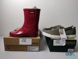 two pairs of red and green rain boots sitting on top of boxes