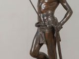 bronze statue of a man holding a spear on a wooden table