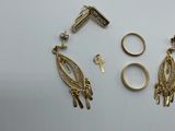 three gold rings and a pair of gold earrings on a white surface