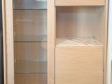 a wooden cabinet with glass doors and shelves in the corner