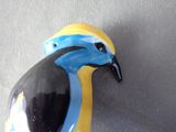 yellow and blue bird figurine sitting on top of a gray surface