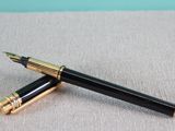 two black and gold fountain pens sitting next to each other on a table