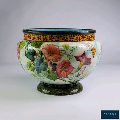 un vase avec des fleurs peintes dessus, posé sur une table