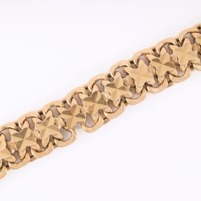 a close up of a gold bracelet on a white surface