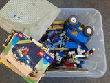 un bac rempli de Lego et de livres posé par terre