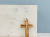 une croix en or posée sur un bloc de marbre blanc, sur fond bleu