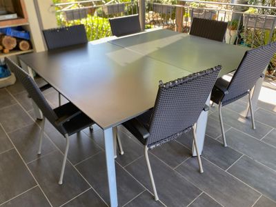 a table and chairs on a patio with a balcony in the background