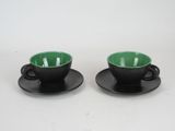pair of black and green cups and saucers on saucers
