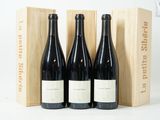 trois bouteilles de vin rouge dans un coffret en bois posé sur une surface blanche
