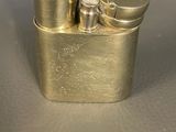 a close up of a metal lighter with a hand on top of it