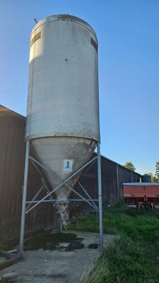 a large white silo sitting next to a red truck