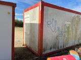 a red and white container sitting in the middle of a field