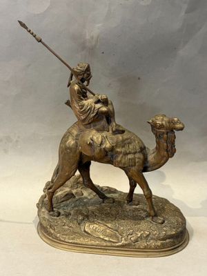 bronze statue of a man riding a camel with a spear in his hand