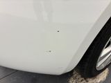 the front end of a white car with dirt on the ground