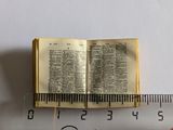 a miniature book on top of a ruler next to a ruler