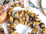 a necklace of tiger ' s eye beads and a pair of scissors
