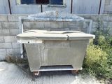 a dirty box sitting outside of a building next to a bush