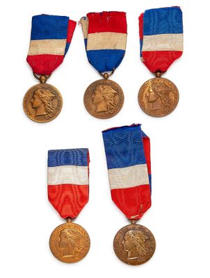 Plusieurs médailles sont exposées sur un fond blanc, accompagnées de rubans rouges, blancs et bleus