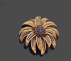 broche en forme de fleur en or et saphir sur un fond noir