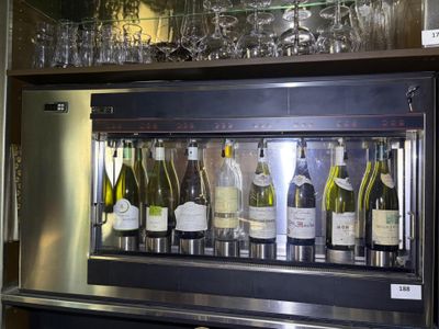 bottles of wine are lined up behind a wine cooler in a bar