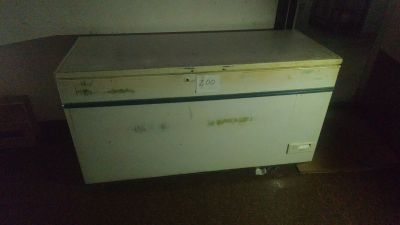 a small white refrigerator in a room with a brown floor