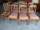 quatre chaises en bois avec des coussins rembourrés roses et une chaise en osier