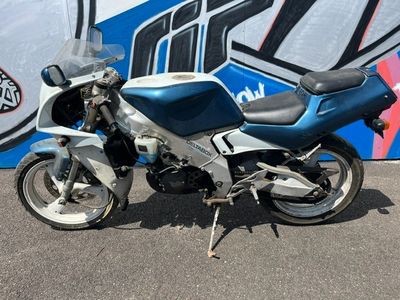 une moto bleue et argentée garée devant un mur