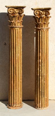 pair of antique brass columns on a white wall with a shadow