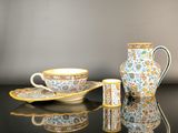 a vase, cup, and saucer sitting on a table