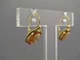 paire de boucles d'oreilles en or et corail, ornées de perles, présentées sur un support en acrylique transparent