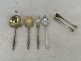 five silver spoons and two silver spoons on a white surface