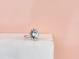 un gros plan d'une bague sertie d'un diamant blanc posée sur un bloc de marbre