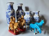 Plusieurs vases et figurines sont posés sur une surface blanche
