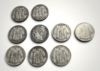 six types différents de pièces d'argent sont disposés sur une surface blanche