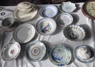 de nombreuses assiettes et bols posés sur une table, avec une horloge en arrière-plan