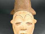 a close up of a wooden mask with a hat on it