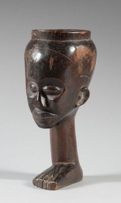 une image représentant un vase en forme de tête en bois posé sur une surface blanche