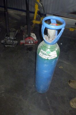 une bouteille de propane bleue posée dans un garage à côté d'une paire de chaussures