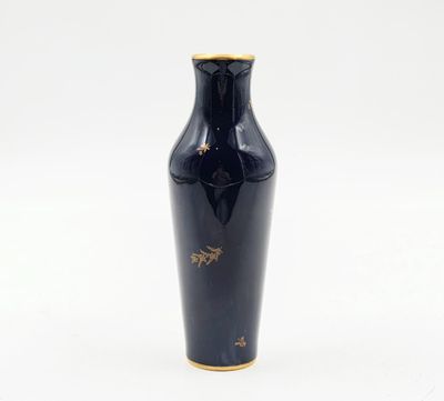 un vase noir orné de motifs dorés sur un fond blanc