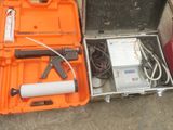 une mallette orange contenant des outils, posée par terre