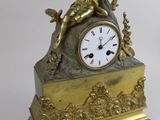 a gold clock sitting next to a key on a table