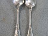 pair of silver spoons sitting on top of a gray surface