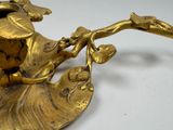 a gold vase with a bird on it on a white table