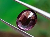 un gros plan sur un diamant violet tenu par une pince