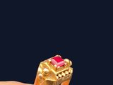 quelqu'un tient une bague en or sertie d'une pierre rose