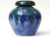 a blue vase with a green lid sitting on a white surface